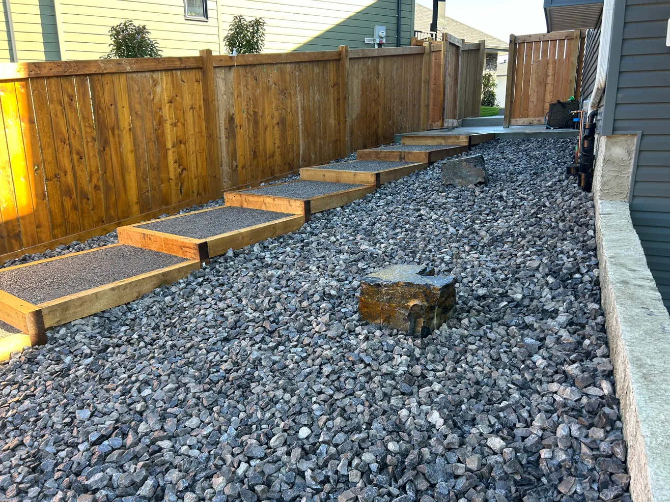 Staircase in the process of having its wood refinished and stained by FHG Contracting walkway in a backyard with lots of drainage rocks everywhere