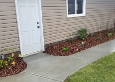 Concrete walkway beside a house by Lush Landscaping