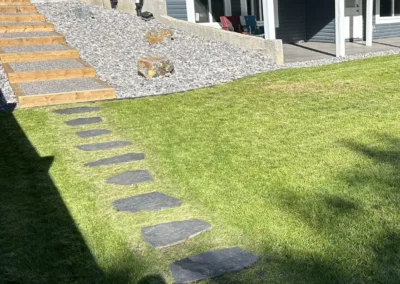 a backyard with a stone walking path made by Lush Landscaping
