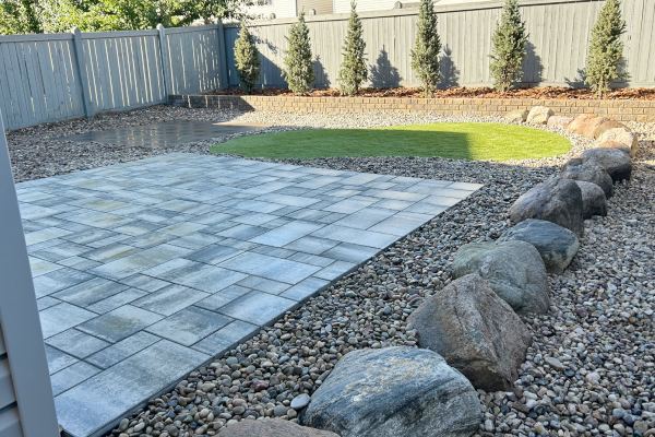 backyard patio with draining rocks beside it in a backyard