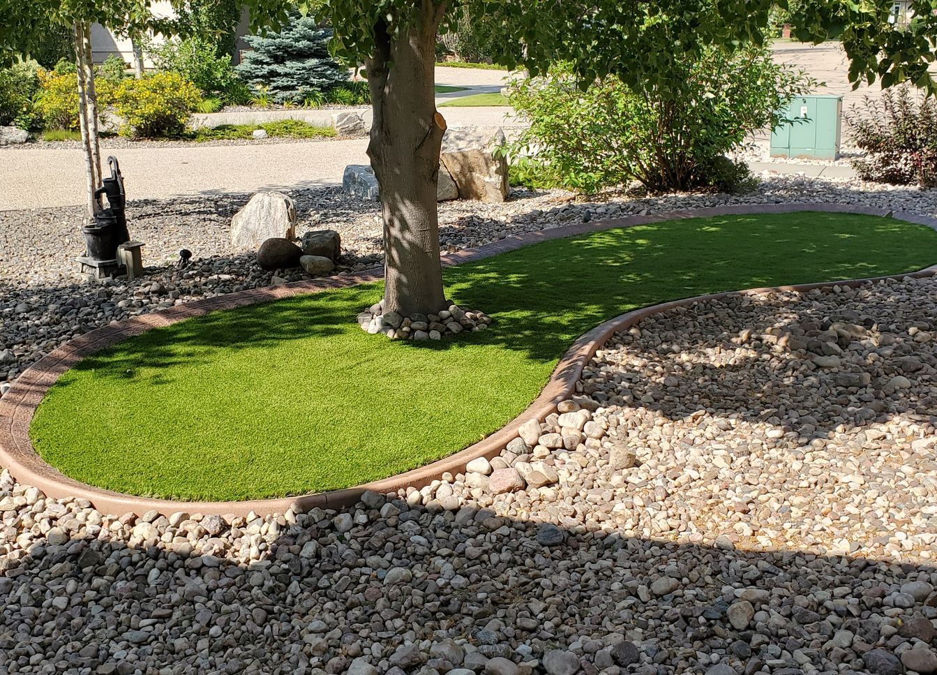 stone and tree and grass yard hardscape design by Lush Landscaping