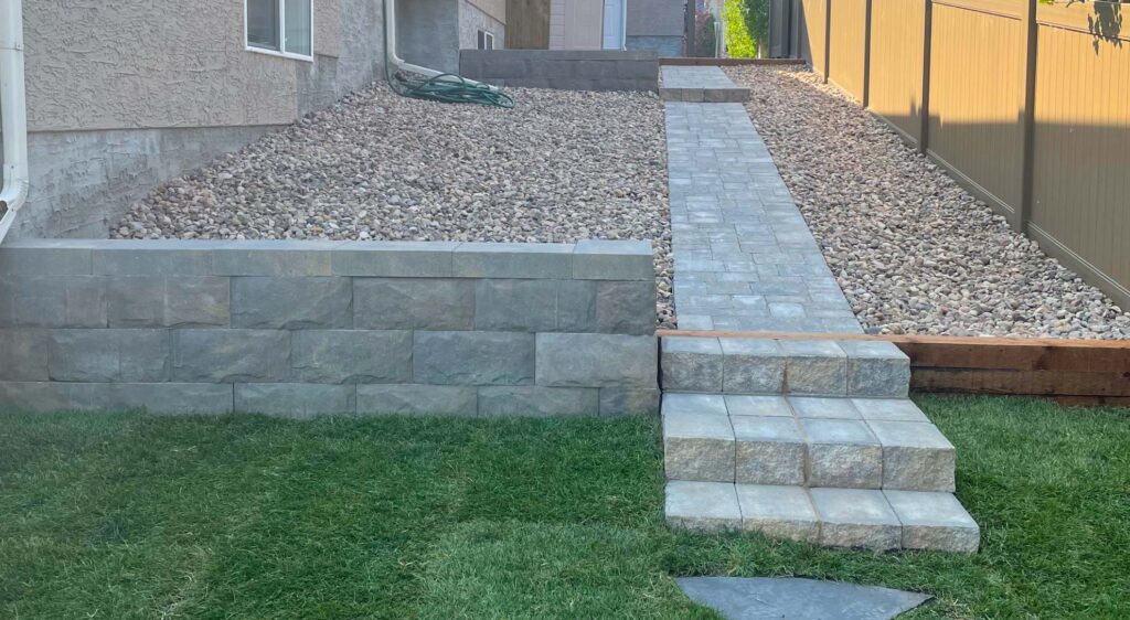stone walkway and steps next to retaining wall in backyard by Lush Landscaping