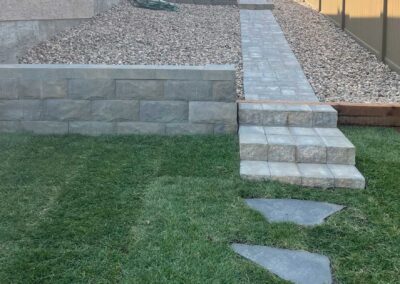 stone walkway and steps next to retaining wall in backyard by Lush Landscaping