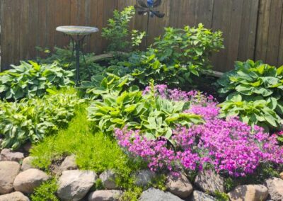 Flowers, plants and bushes planted in a backyard garden by Lush Landscaping
