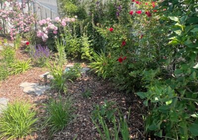 Flowers, plants, mulch and bushes planted in a backyard garden by Lush Landscaping