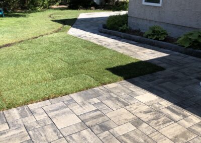 Stone patio and walkway in a backyard by Lush Landscaping