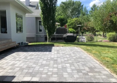 a stone patio behind a house in Edmonton built by Lush Landscaping