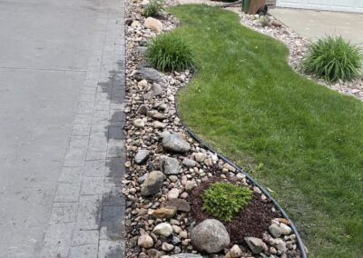 Decorative rocks next to a driveway by Lush Landscaping