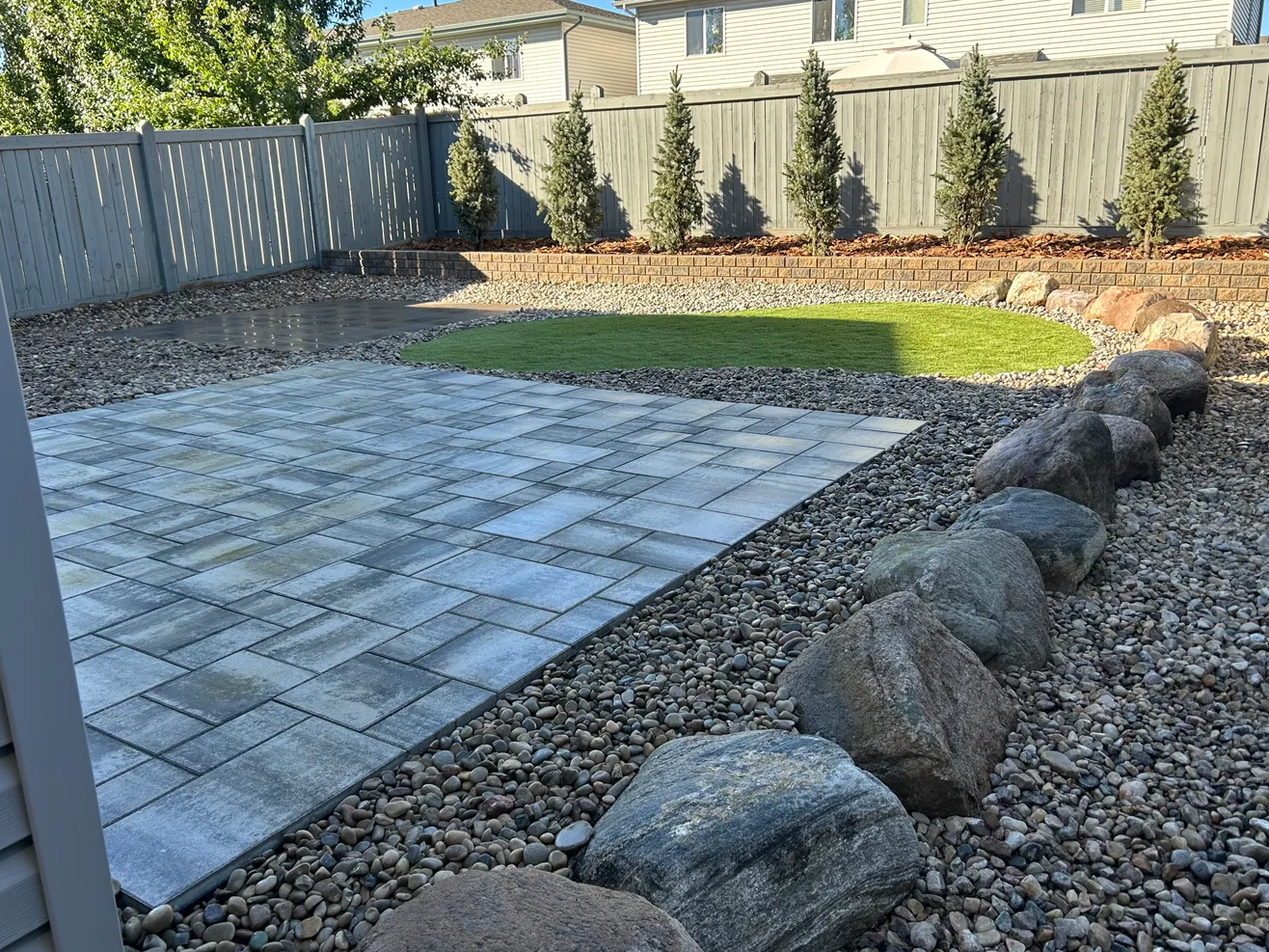 Decorative boulders and a new stone patio built by Lush Landscaping
