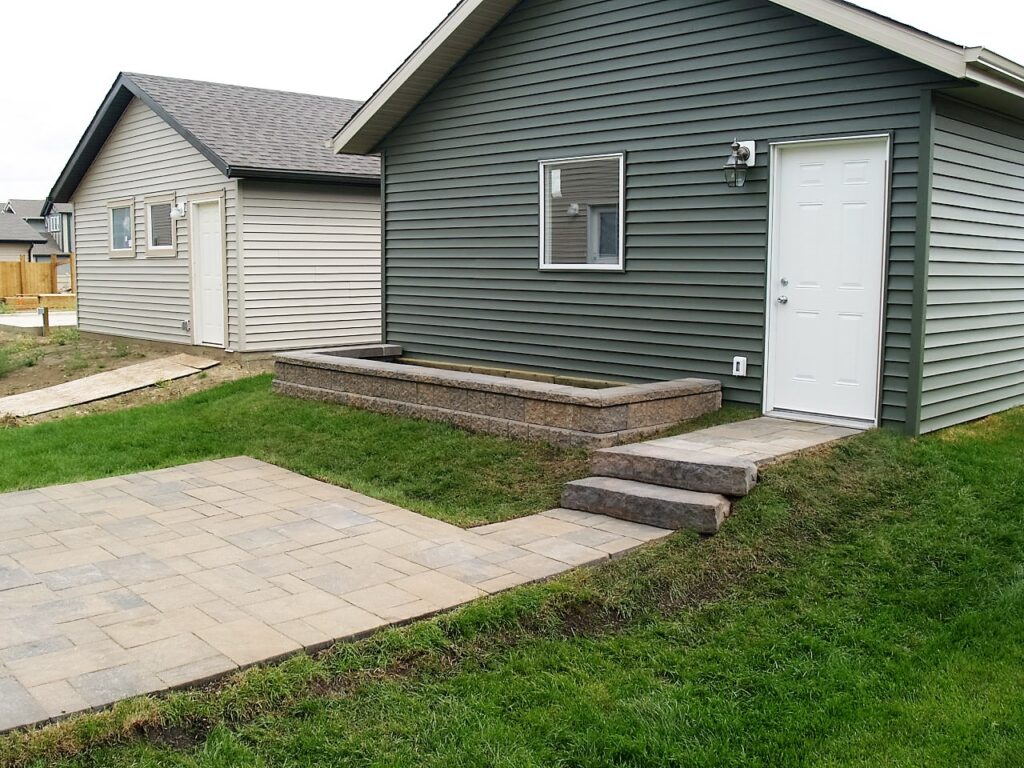 Stone patio and steps in front of a garage by Lush Landscaping