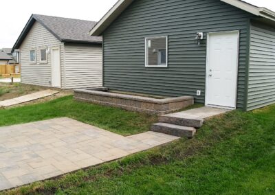 Stone patio and steps in front of a garage by Lush Landscaping