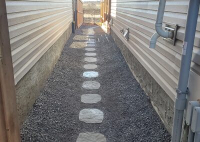 Stone walkway between two houses by Lush Landscaping
