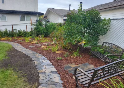 a backyard with a nice walkway mulch and a bench installed by Lush Landscaping in Edmonton
