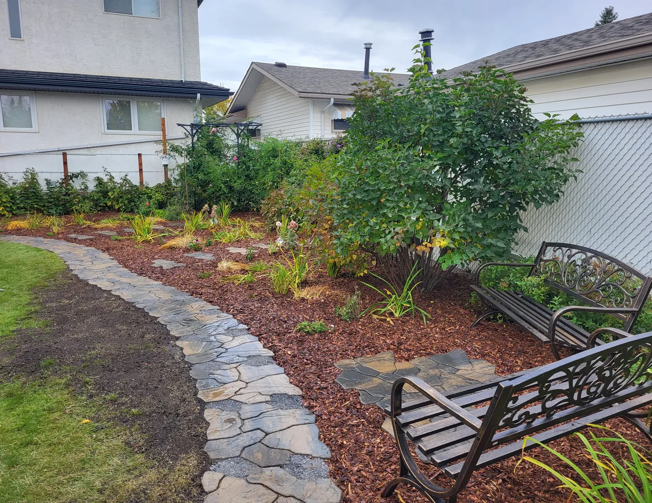 Backyard with a walkway, mulch and a bench installed by Lush Landscaping in Edmonton a backyard with a nice walkway mulch and a bench installed by Lush Landscaping in Edmonton