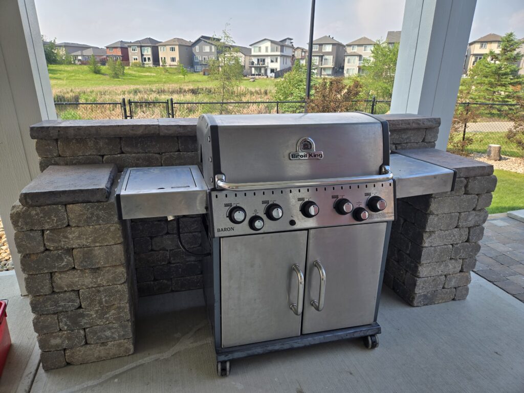A stone wall around around a backyard grill that was constructed by Lush Landscaping