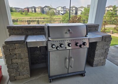 A stone wall around around a backyard grill that was constructed by Lush Landscaping
