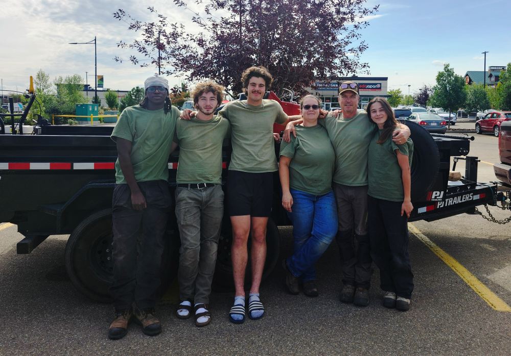 Lush Landscaping team in Edmonton Alberta Canada in a parking lot standing in front of their work trailer getting ready to do landscaping work