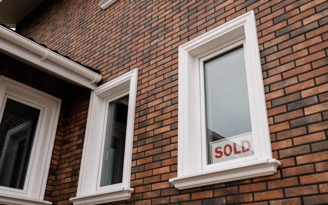 a brick house with a sign in the window that says SOLD
